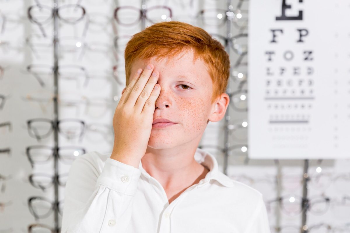 cute-boy-covered-his-eye-with-hand-standing-optics-clinic_23-2148241527