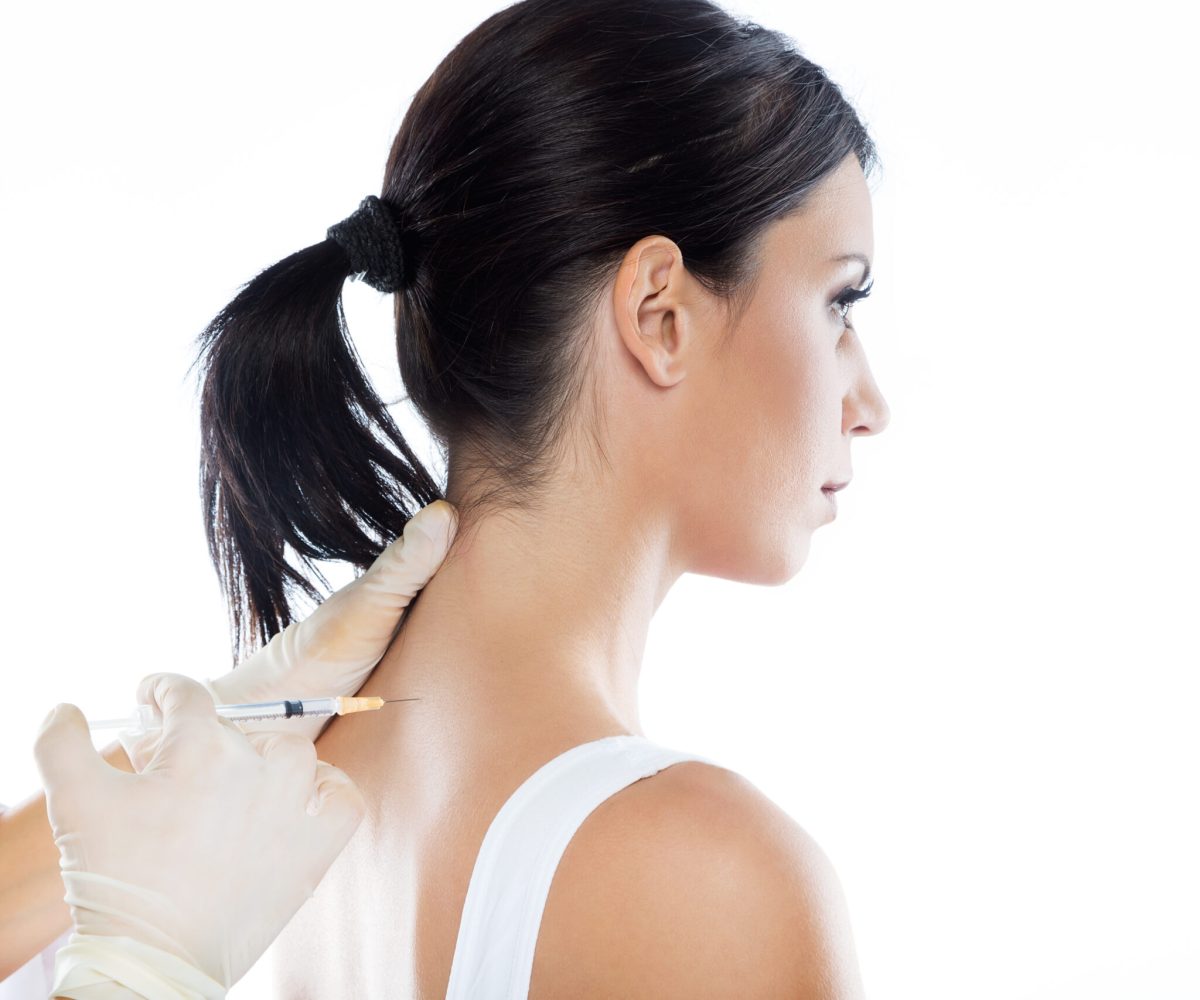 Portrait of surgeon making injection into female body. Neural therapy concept.
